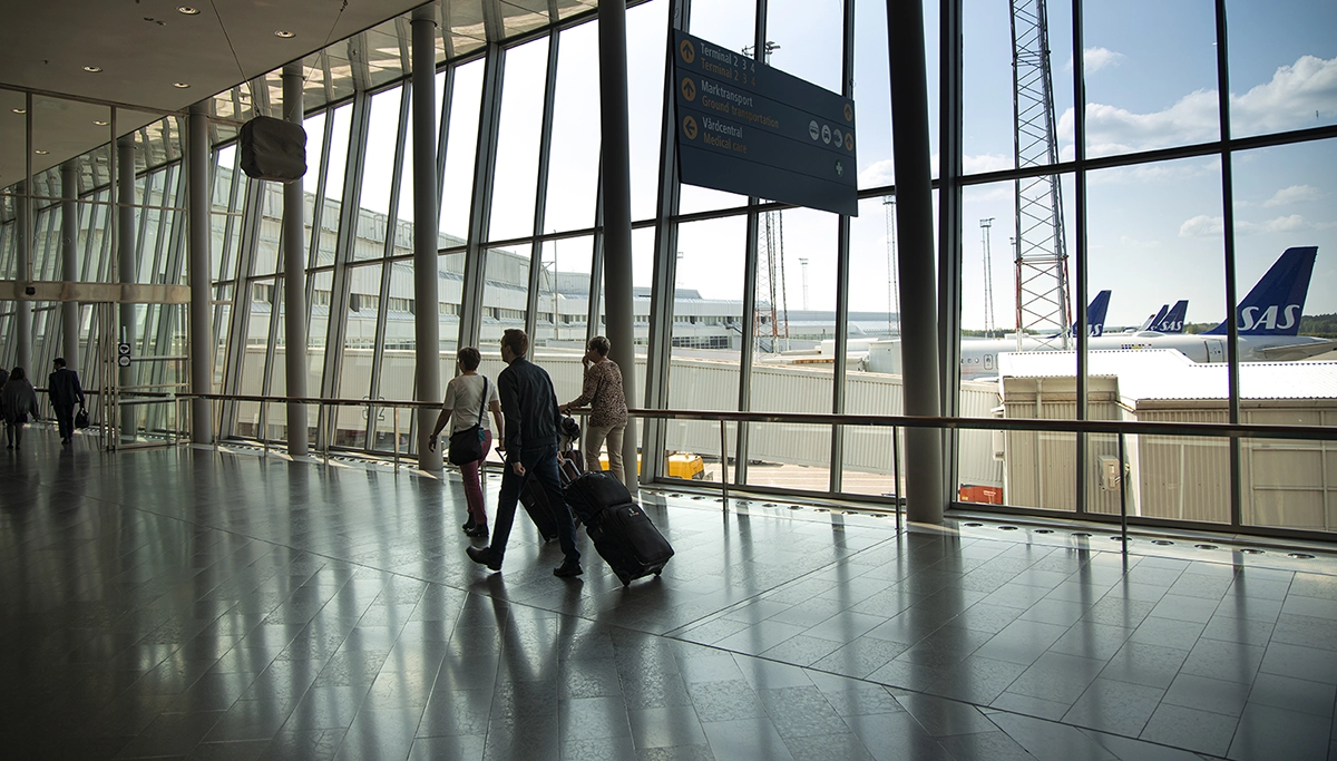 People walking through an airport with suitcases.