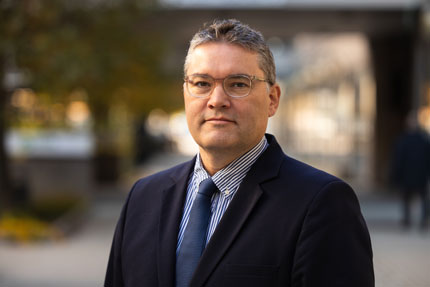 Portrait of Marcus Toremar, Director Digitalisation and Development Department. He stands outside in a striped shirt, a dark tie and a dark jacket.