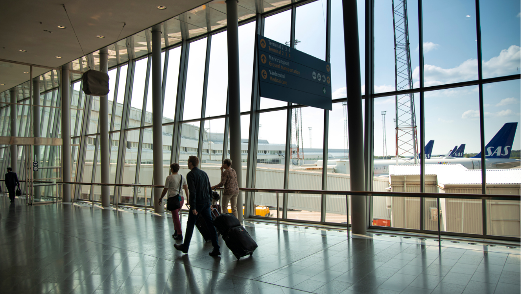 People walking through an airport with suitcases.